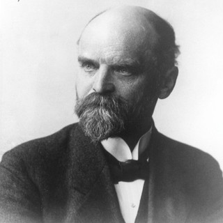a grayscale photo portrait of Ferdinand Tönnies. He has a balding head of hair, a full beard that comes to a point, and an intensely focus look in his eyes.